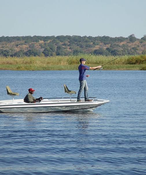 Two people fishing from a boat on the Chobe River